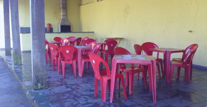 salão de festas com diversas mesas e cadeiras; churrasqueira ao fundo